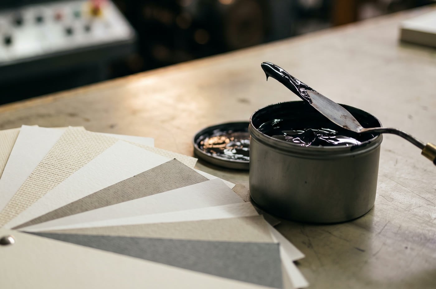 Paper samples fanned out beside an open tin of black ink
